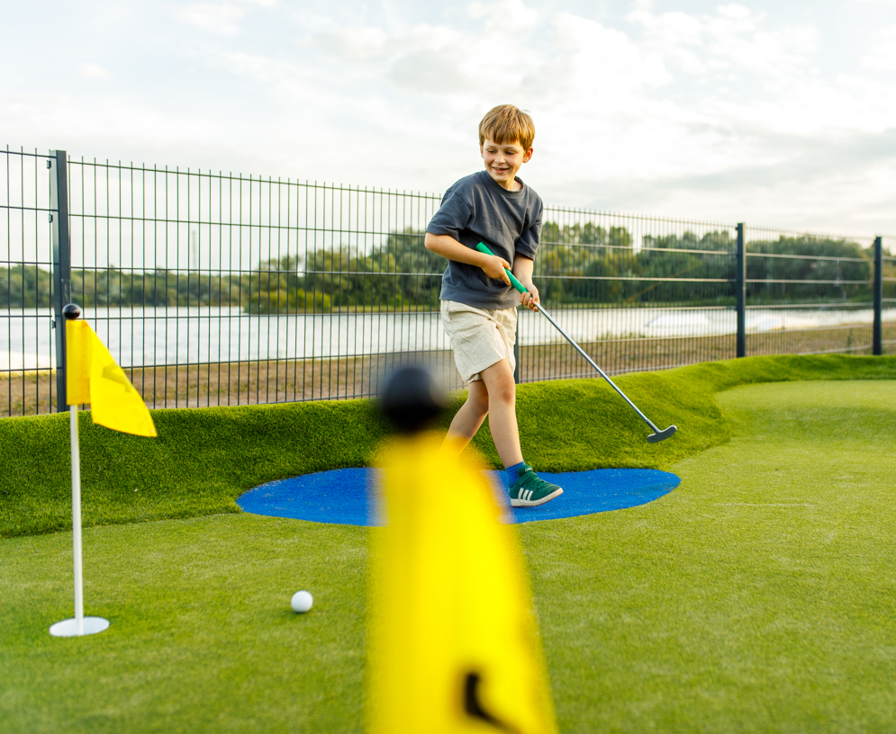 Kleiner Junge spielt seine Ball auf der Gulf Golf Anlage.