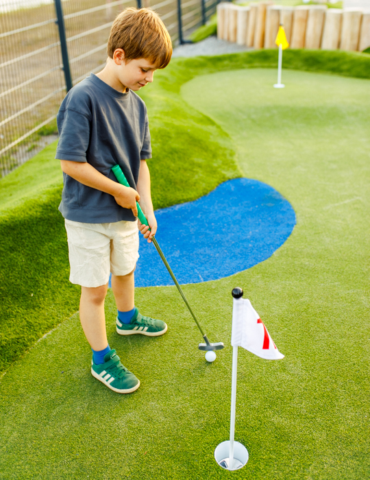 Kind spielt Minigolf auf dem Übungsgreen