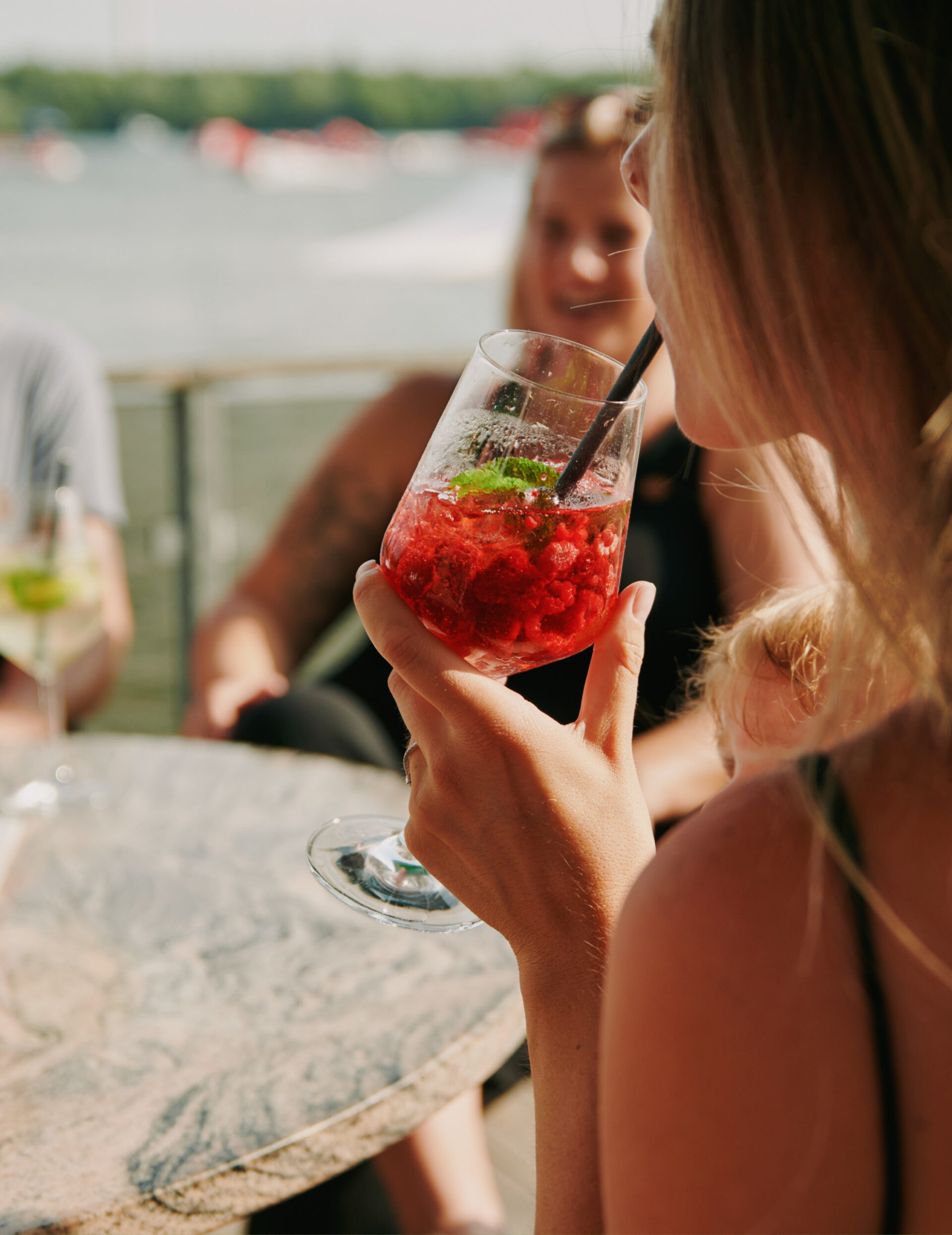 Junge Frau trinkt Aperol Spritz auf Hooksieler Skiterrassen.